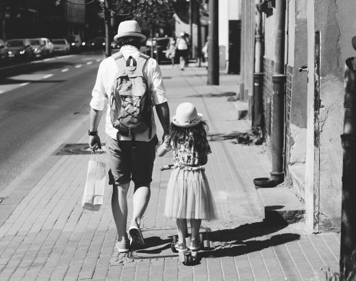man holding girl while walking on street